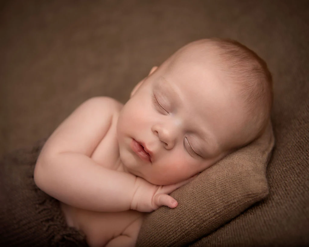 Ruben asleep on a soft brown blanket.